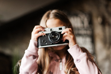 The girl with the camera. Film camera. A child and a film camera. No focus.