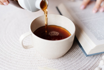 Pouring tea into a mug. Reading a book and tea. Flavorful tea and a book. 