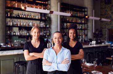Portrait Of Female Owner Of Restaurant Bar With Team Of Waiting Staff Standing By Counter