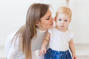 Young mother playing with her baby girl at home. Motherhood, infant and children concept.