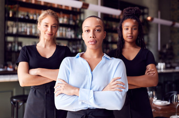 Portrait Of Female Owner Of Restaurant Bar With Team Of Waiting Staff Standing By Counter