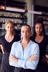 Portrait Of Female Owner Of Restaurant Bar With Team Of Waiting Staff Standing By Counter