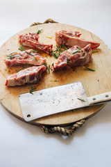 Raw Lamb Chops cut on a wooden rounded cutboard over a white background,  big butcher knife on the side