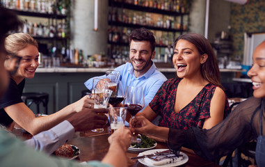 Group Of Friends Meeting In Restaurant Celebrating And Making A Toast