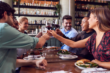 Group Of Friends Meeting In Restaurant Celebrating And Making A Toast