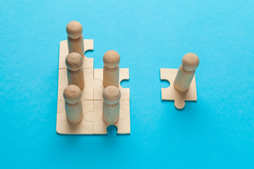 Wooden figures on puzzles on blue background as a symbol of team building. Organization group people in business. Cooperation and partnership.