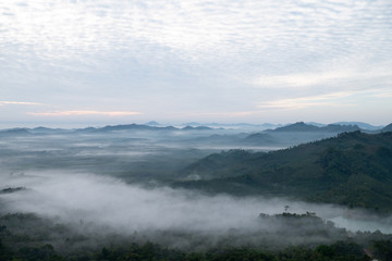 Nature scenery view of misty mountain with fog in summer morning and cloudy sky