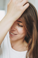 Close up portrait of smiling young woman brown hair and green eyes with freckles in white t-shirt