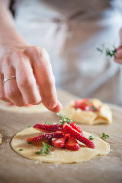Une main dispose des fraises sur une tartelette