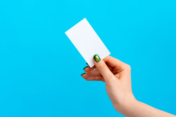 Woman hand holding blank card on blue background, close up.