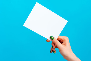 Woman hand holding blank card on blue background, close up.