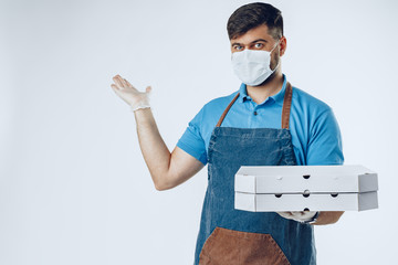 Fototapeta na wymiar Pizza delivery man in medical gloves and mask against grey background. Safe service while coronavirus covid-19 outbreak