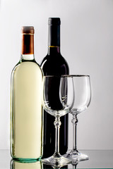 Two bottles of wine with tap and white wine and two glasses on a thin stem.