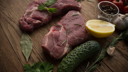 Raw juicy meat steaks ready for roasting on a wooden background