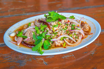 Spicy minced pork salad, minced pork mash with spicy, Thai food style. on the wooden table.
