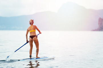 Naklejka premium Sports girl on a board for glanders surfing in the sea