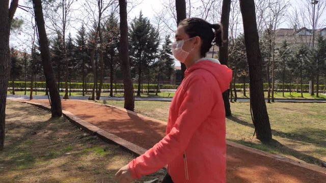 Woman with medical face mask is walking in nature