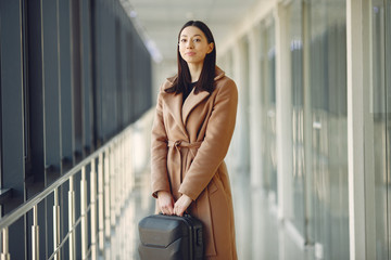 Woman at the airport. Girl with suitcase. Lady in a brown coat.