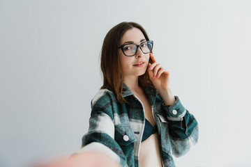 Beautiful woman in underwear and a plaid shirt takes a selfie.