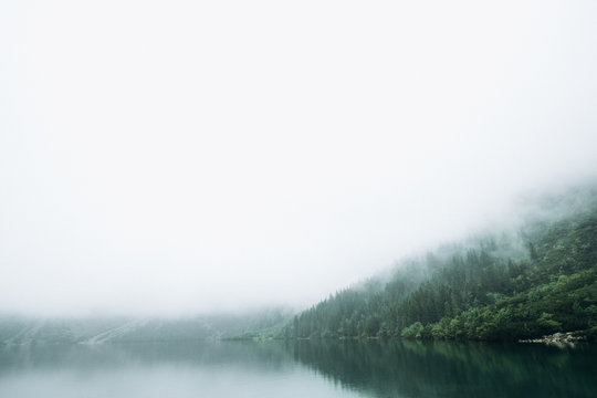 Beautiful view of the lake in the mountains in foggy weather. © Oksana