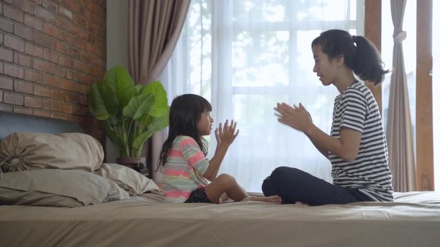mother and child playing highfive on the bed in the morning