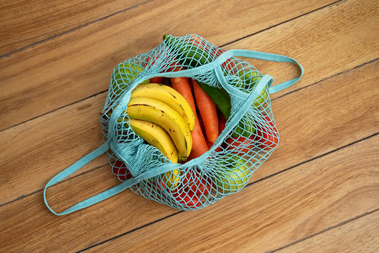 Cotton string eco bag with fruits and vegetables on wooden background