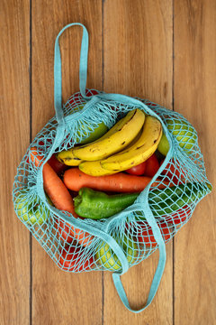 Cotton string eco bag with fruits and vegetables on wooden background