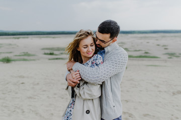 A young woman and a man walk, hug and kiss in a sand quarry.