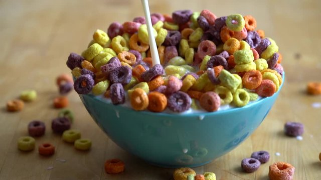 Milk pouring into colourful bowl of cereal, slow motion.