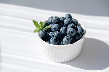 fresh Blueberry in a white bowl. antioxidant organic superfood concept for healthy eating and nutrition. bluberries under sunlight. meal for heart health