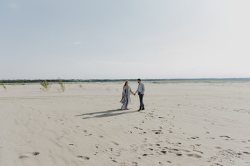 A young woman and a man walk, hug and kiss in a sand quarry.
