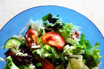 Fresh vegetables in a blue bowl. Mix. Salad of vegetables and herbs