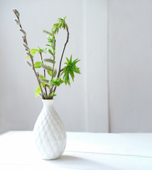 spring branches in a white vase on a table. fresh and minimal style concept. clean and uncluttered room. scandinavian design. 