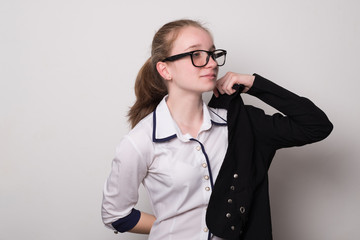 Happy girl in glasses puts on a jacket. Charming caucasian girl in glasses.