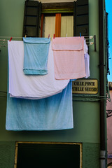 Washed clothes hanging outside the windows in the street of Chioggia with the street name, near Venice in Italy.