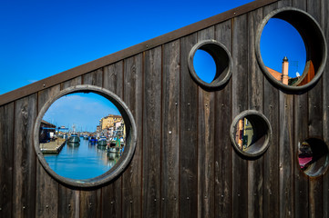 Chioggia, town in venetian lagoon, city view through the holes of a wooden bridge. Veneto, Italy, Europe.