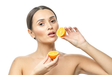 Close up beauty portrait of an excited attractive half naked woman holding Meyer lemon slices at her face and looking at camera isolated over white background