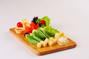 Cheese platter, red and green pesto cheese, lettuce tomatoes on the wooden board