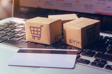 Online shopping - Paper cartons or parcel with a shopping cart logo and credit card on a laptop keyboard. Shopping service on The online web and offers home delivery..