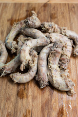 Bunch of fresh cooked chicken necks set on a wooden board in a kitchen