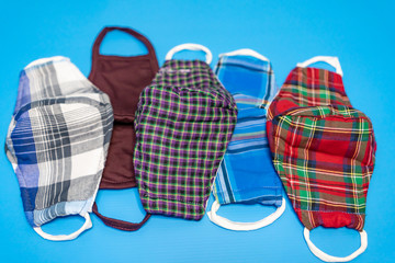 Different colors of washable face masks on blue background. Fashionable face masks reusable and washable