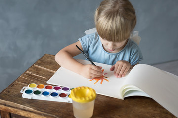 a little girl paints in the album the sun sitting at the table