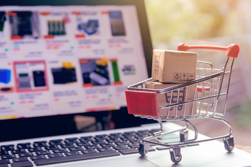 Shopping online. cardboard box with a shopping cart logo in a trolley on laptop keyboard. Shopping...