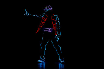 Dancer in suits with LED lamp. Silhouette of a man in a luminous suit on a black background. Neon...