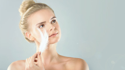 Portrait of attractive girl with closed eyes. beautiful woman with a white feather near her face....