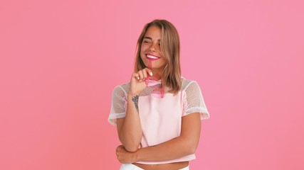 Female with shiny freckles, dressed in top. Flirting and smiling, taking off her sunglasses and winking, posing on pink background. Close up - Powered by Adobe