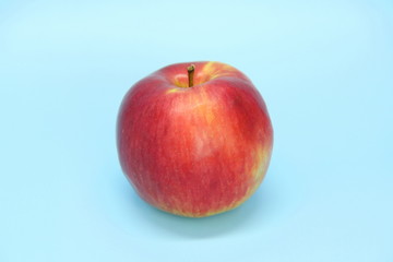 Red yellow apple on a blue background. Juicy ripe beautiful fruit.