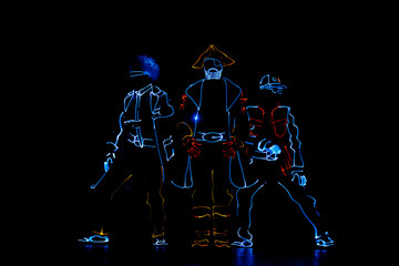 Silhouettes of dancing people in luminous costumes on a black background. LED suit.