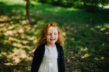 Naklejka premium portrait of a little red-haired girl in Apple trees