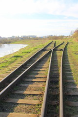 The railway stretching into the distance against the background of young green grass and trees in spring.